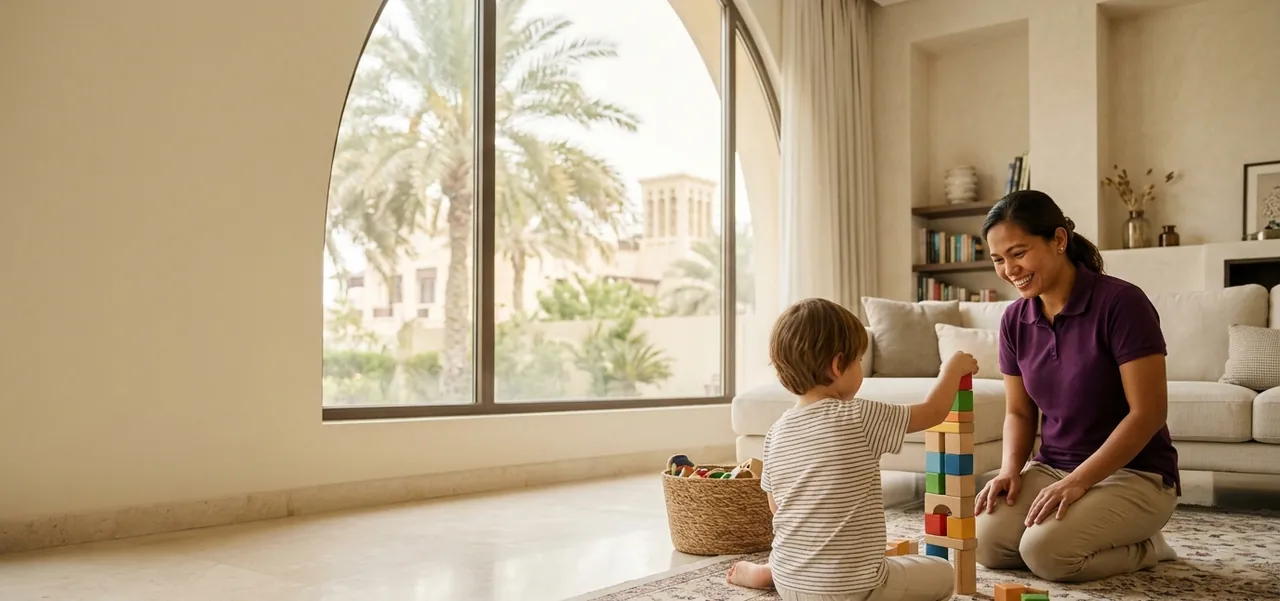 A nanny building a tower of blocks with a child at home in Dubai